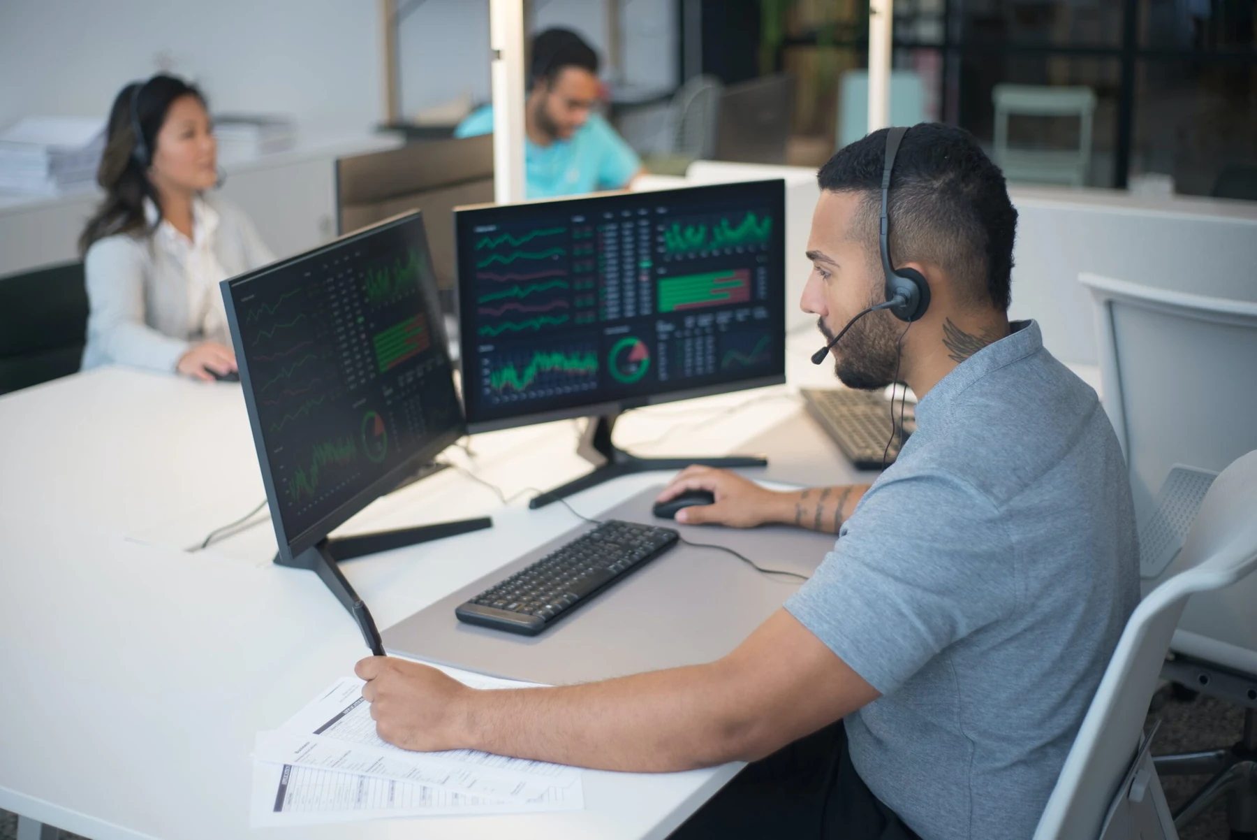 An office worker wearing a headset at a multi-monitor workstation