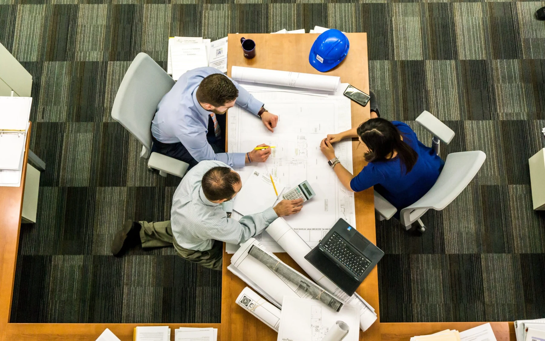 Three colleagues reviewing plans around an office table